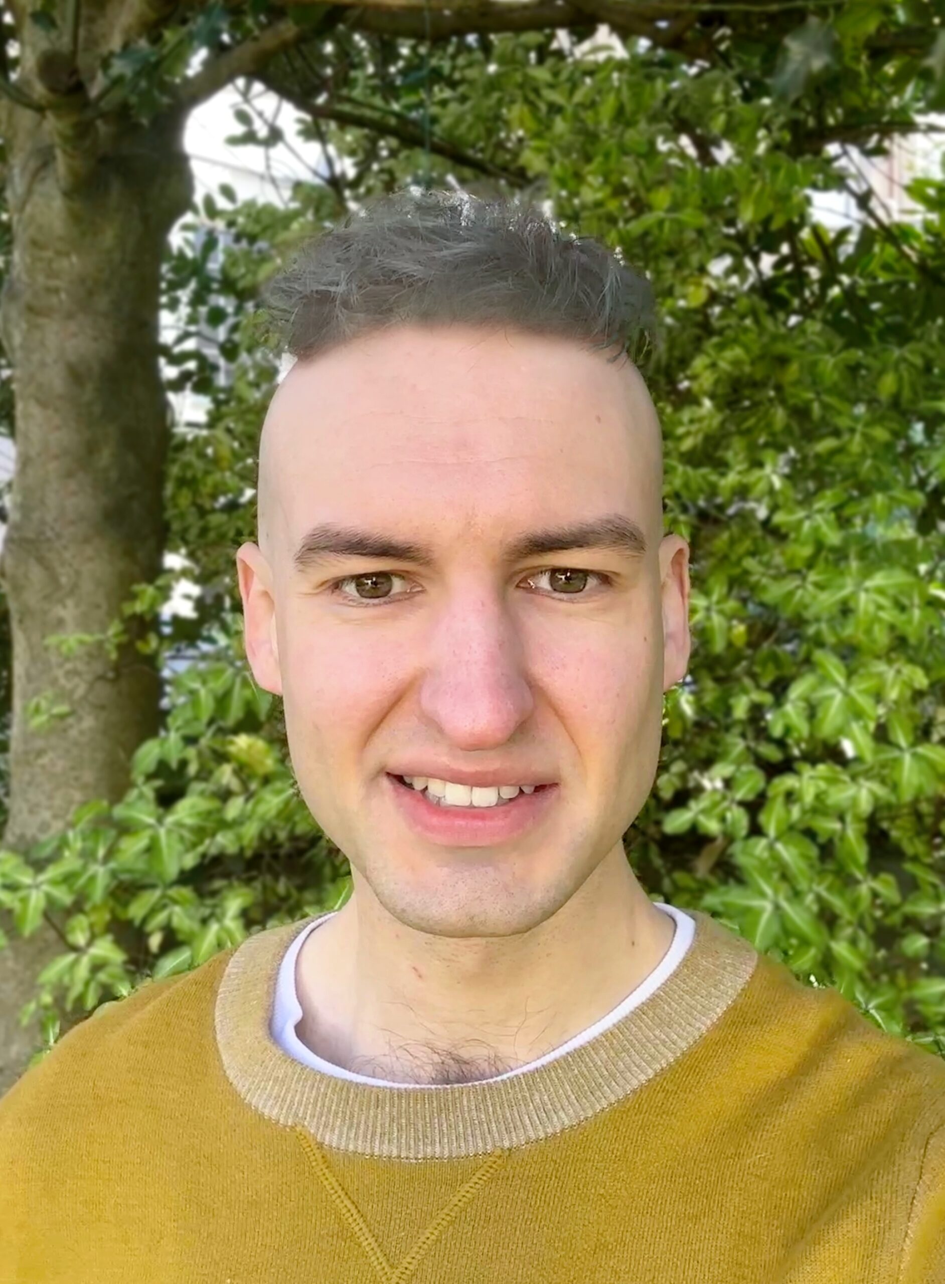 headshot of Steven Gamble, a white man in his early 30s with short dyed hair, foliage in the background